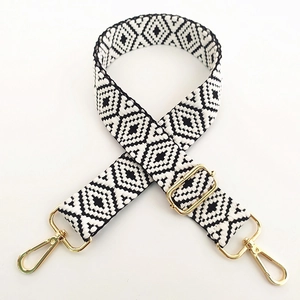 Detail of adjustable black and white geometric woven bag strap with gold metal hardware
