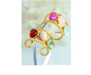 Macro shot of 18K gold plated ring with colorful cabochon gems on a glass rim