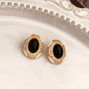 Close-up of vintage flower earrings with black oval stone and white enamel detail