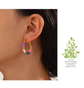 Gros plan d'un mannequin portant des boucles d'oreilles créoles émaillées dorées 18 carats