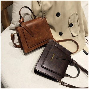 Détail de petits sacs carrés vintage en cuir marron avec des ferrures en bronze antique