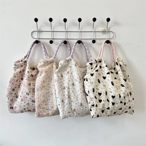 Detail of four cartoon embossed canvas tote bags with rope handles and bubble texture