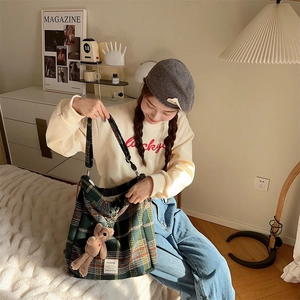 Close-up of green and brown plaid wool tote bag with a cute bear charm in cozy room