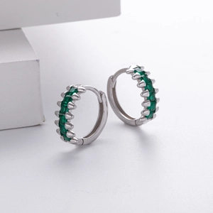 Macro shot of silver hoops with micro-paved green zircon stones on white background