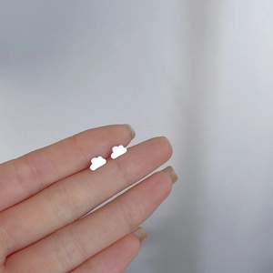 Macro shot of minimalist 925 silver cloud stud earrings held to show mini size detail