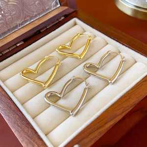 Détail de boucles d'oreilles créoles en forme de cœur dorées et argentées sur velours