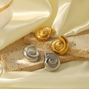 Dettaglio ravvicinato di orecchini a conchiglia oro e argento con trama a spirale lucida