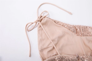 Détail des fines bretelles réglables et des paillettes dorées sur une robe décolletée