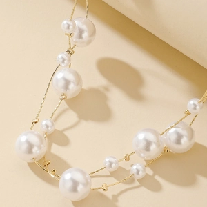 Detail shot of multilayered white pearls and golden metal chains on vintage style necklace
