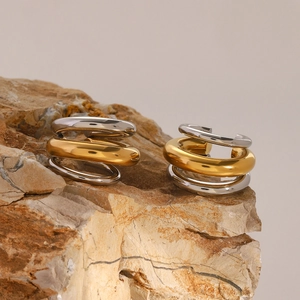 Détail macro de boucles d'oreilles triple couche en acier inox doré et argenté