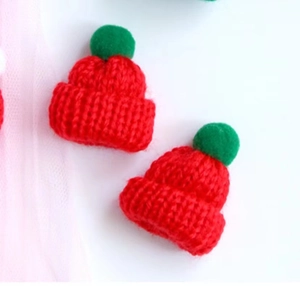 Detailed view of red knitted mini finger hat with a green pompom for DIY crafts