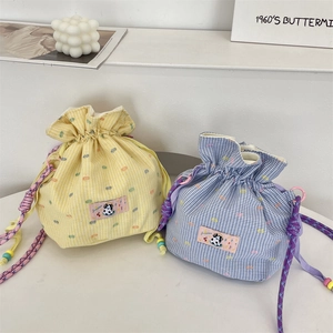 Detail of colorful plaid drawstring bucket bags with cow patch and braided straps