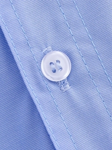 Macro shot of blue woven fabric with white four-hole button and fine stitching details