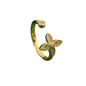 Golden open ring with clover design encrusted with zircon and a single round diamond