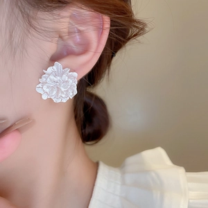 Close-up of elegant 3D white flower stud earring with layered petals on a model