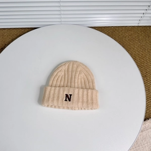 Close-up of beige knit beanie featuring textured ribbing and black letter N embroidery