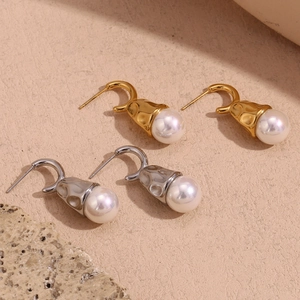 Detail of teardrop pearl earrings with hammered gold and silver irregular metal texture