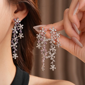 Detail of silver drop earrings with pink and purple zircon flowers and long tassels