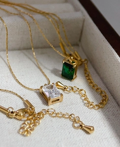 Detail of square emerald and white zircon pendants on 18k gold plated chain necklaces
