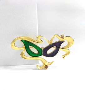 Detail of masquerade mask brooch with green and purple enamel on gold frame