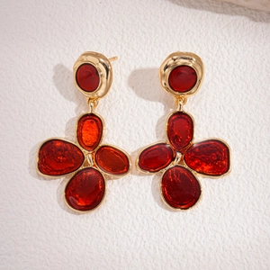 Detail view of red flower enamel earrings with gold metal petals and retro aesthetic