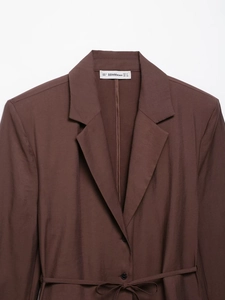 Detail of dark brown blazer texture with woven fabric and adjustable waist belt