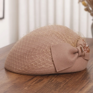 Detail of pink wool beret with mesh veil, oversized bow, and floral bead embroidery