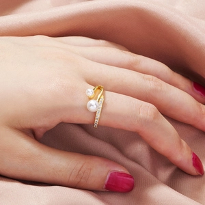 Detail of elegant gold double pearl open ring with cubic zirconia accents on pink silk