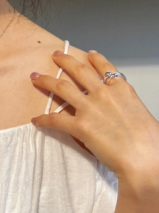 Detail view of a silver teardrop overlapping wrap ring worn on a model finger
