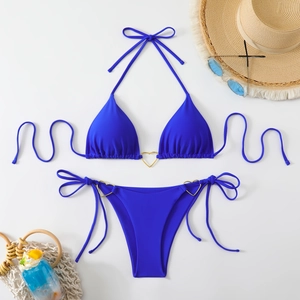 Flat lay of navy blue bikini with gold heart rings and summer vacation accessories