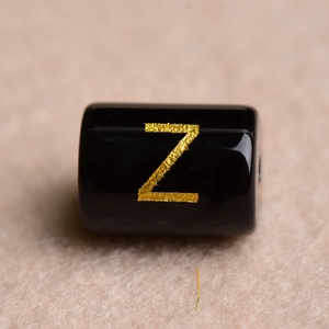 Macro shot of a black resin bead with a gold engraved letter Z for DIY jewelry making