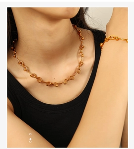 Close-up of gold-plated titanium link necklace and bracelet set on a black tank top