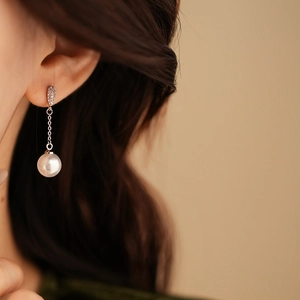 Close-up of model wearing silver zircon studs with a long chain and white pearl drop