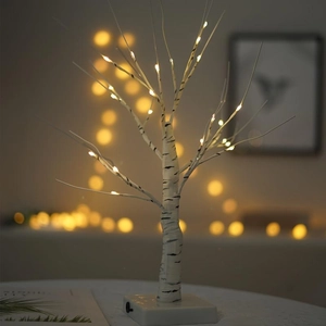 Close-up of LED birch tree lamp showing warm glowing lights and white bark texture