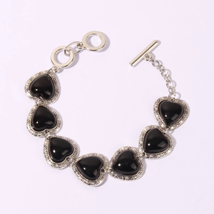 Detail of vintage heart bracelet with black stones and ornate silver scrollwork