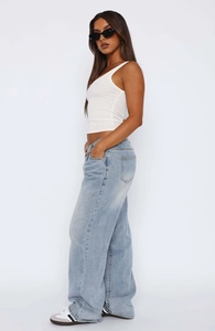 Side view of white ribbed crop top paired with light blue wide leg jeans and sneakers