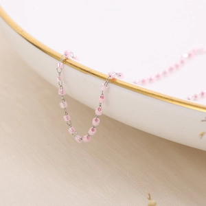 Detail shot of pink pearl beads on a fine silver stainless steel chain over a ceramic plate