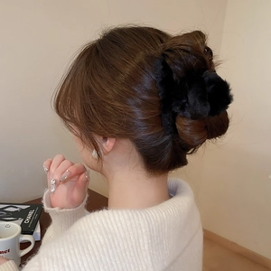 Close-up of black plush cross hair claw clip worn on a bun for autumn winter style