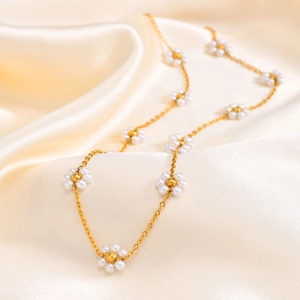 Detailed shot of golden flower necklace with white pearls on champagne silk fabric