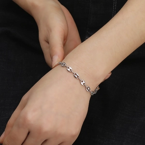 Minimalist silver stainless steel pig nose anchor link bracelet worn on wrist over denim