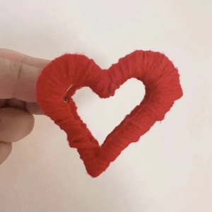 Close-up of red heart-shaped plush hair claw clip with woven wool texture details