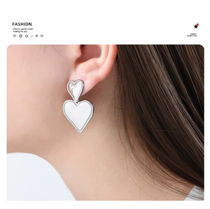 Nahaufnahme von eleganten Doppel-Herzsteckohrringen in Silber, getragen von einem Modell