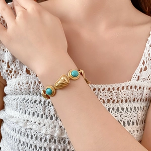 Gros plan d'un bracelet vintage doré avec pierres turquoises rondes et maillons en coquillage