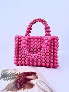 Pink handmade acrylic pearl beaded handbag for women on a magazine background