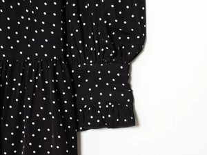 Detailed macro view of black ruffle sleeves and white polka dot pattern on summer dress