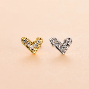 Detail of heart stud earrings in gold and silver finish with sparkling zircon stones