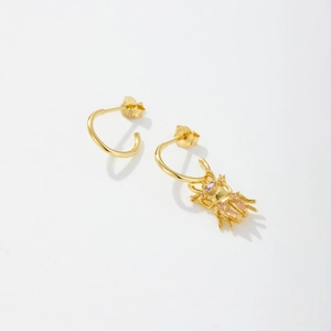 Boucles d'oreilles scarabée dorées avec zircons violets et pierres colorées sur fond blanc