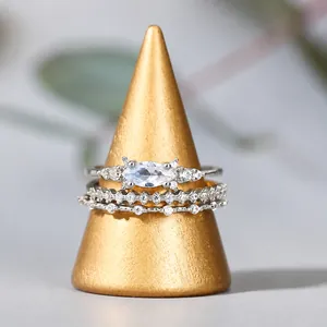 Makroaufnahme von dreiteiligem Silberring-Set mit Marquise-Schliff auf goldenem Ständer