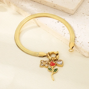 Close-up of gold snake chain bracelet with red enamel rose and zircon charms