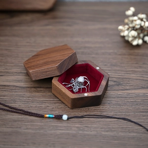 Detail of hexagonal walnut wood jewelry box with luxury red velvet lining and necklace